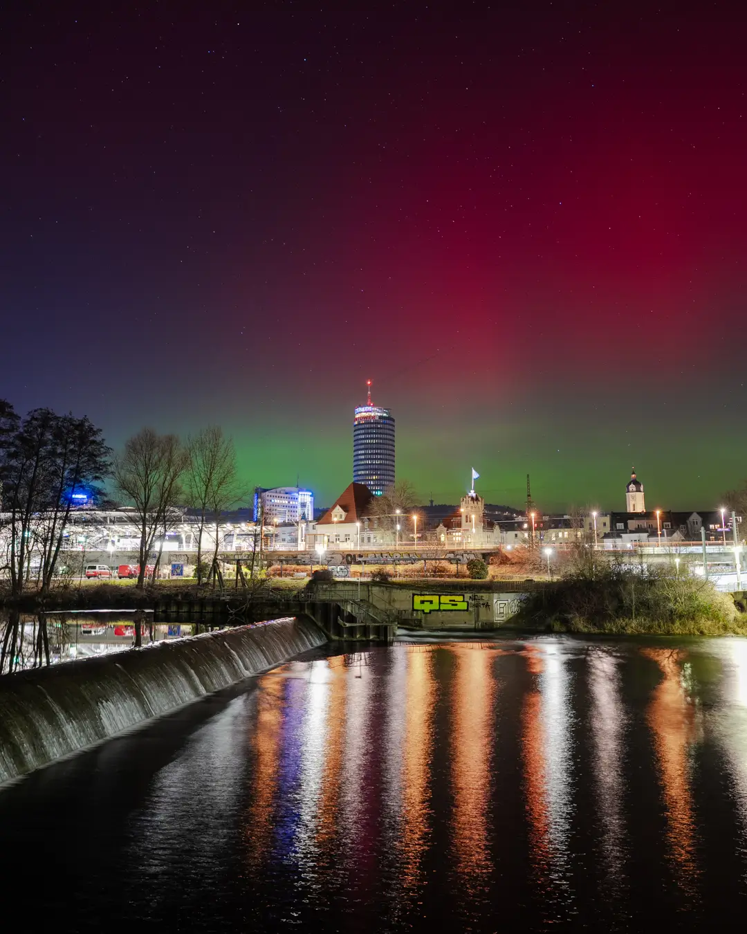 Fotografie von Jena mit grünen und roten Nordlichtern über dem JenTower