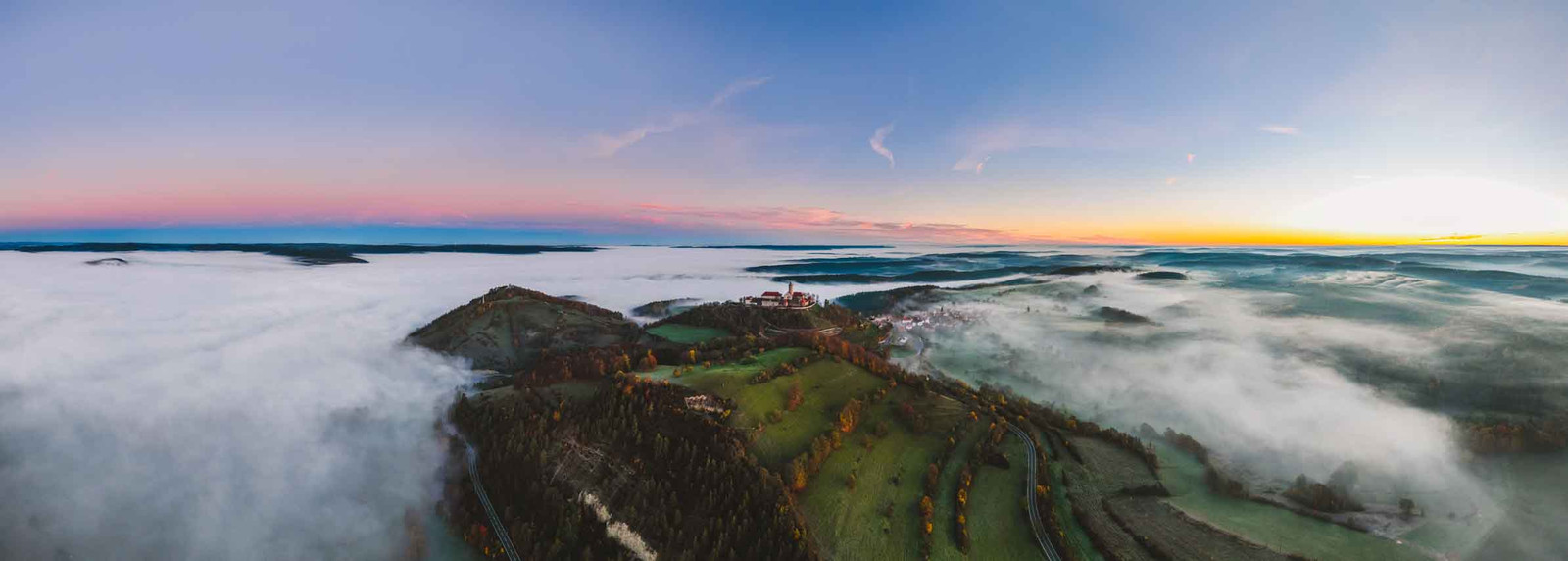 Episches Panorama Foto mit der Leuchtenburg vor Sonnenaufgang über dem Nebel