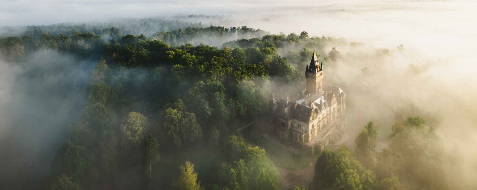 Panorama Foto von Schloss Hummelshain bei Sonnenaufgang mit Nebel